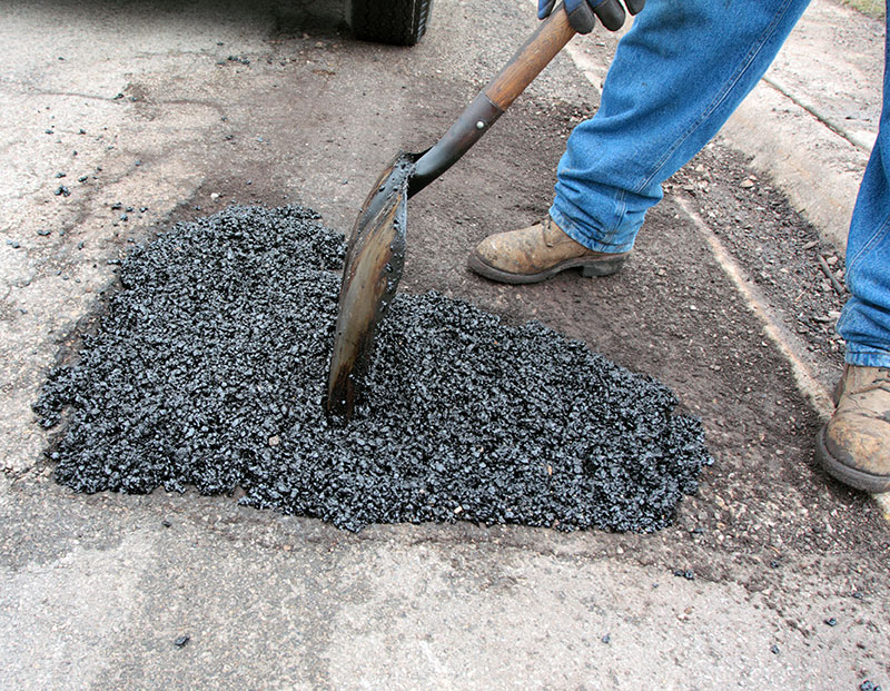 man repairing pothole
